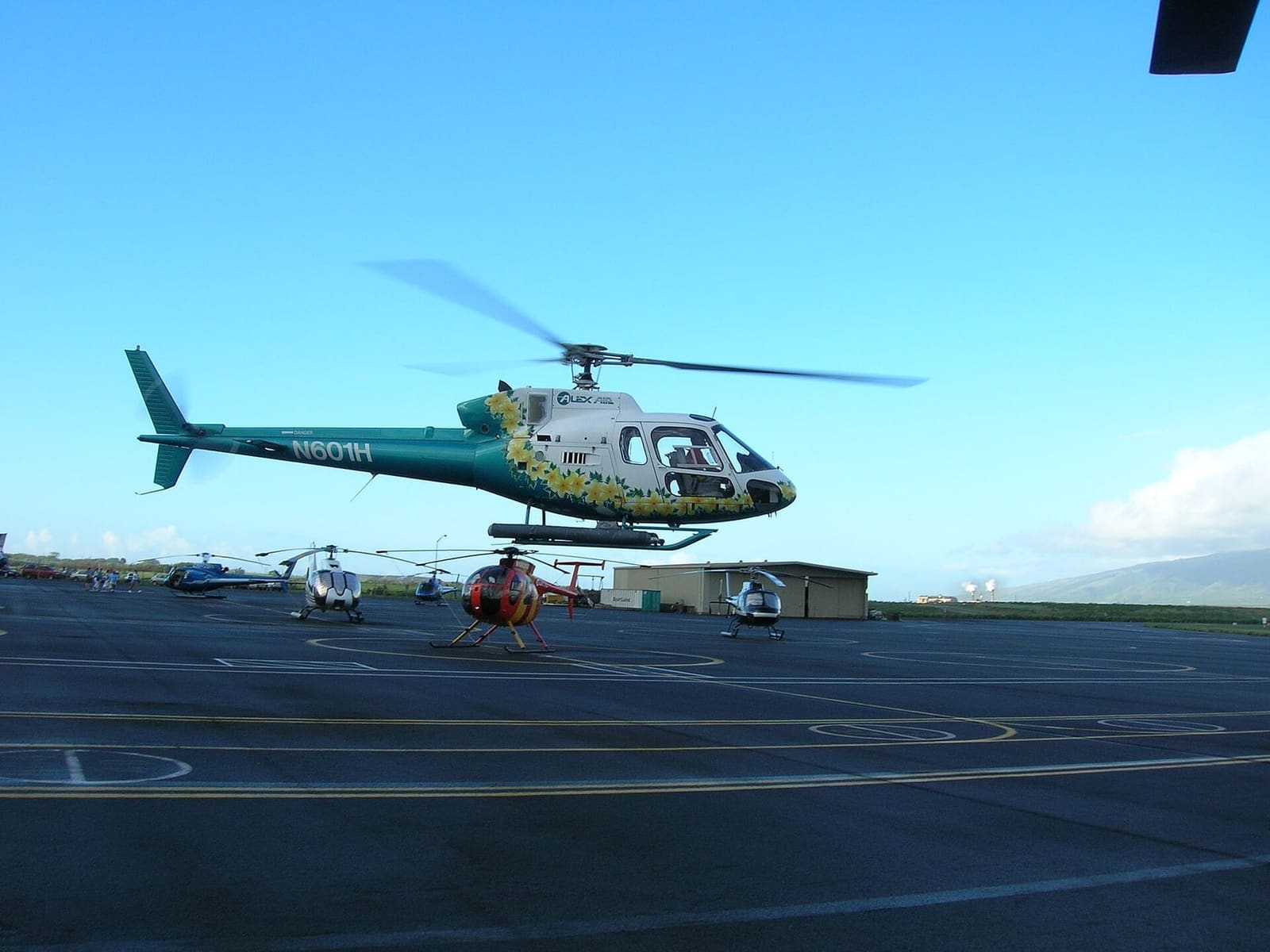 Helicopters parked on the ramp at Kahului Heliport with an Airbus AS350 in the foreground