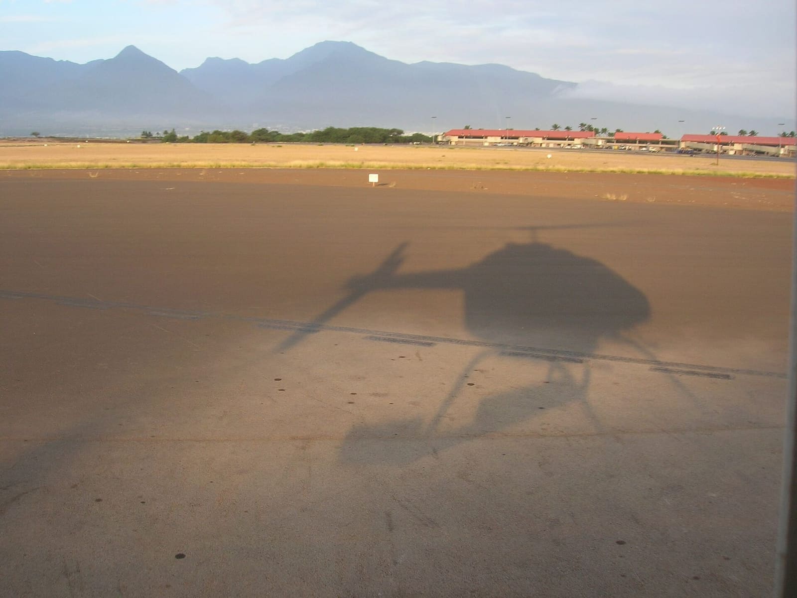 A helicopter's shadow on the Kahului Heliport ramp: weigh-in and briefing happen before every flight