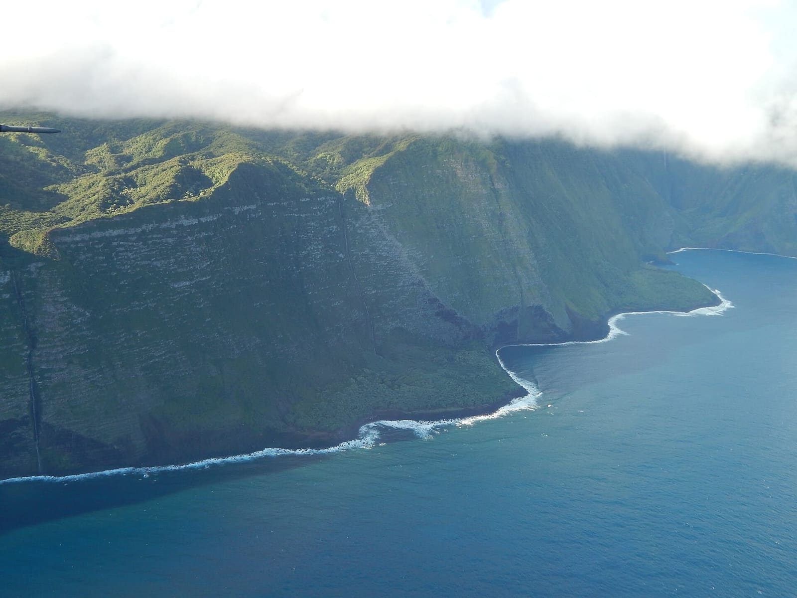 Molokai's north-shore pali and a waterfall from the air: the frame every Maui flight is trying to give you